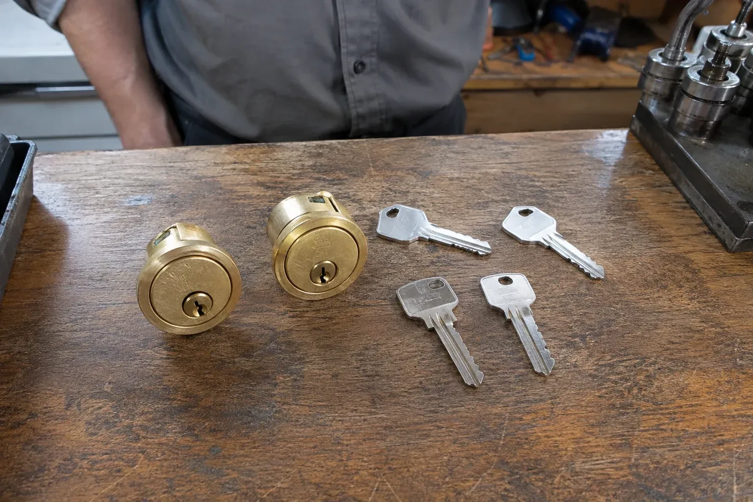 Two detached brass lock cylinders and four house keys on a wooden counter. — Lock Rekeying, Kitchener